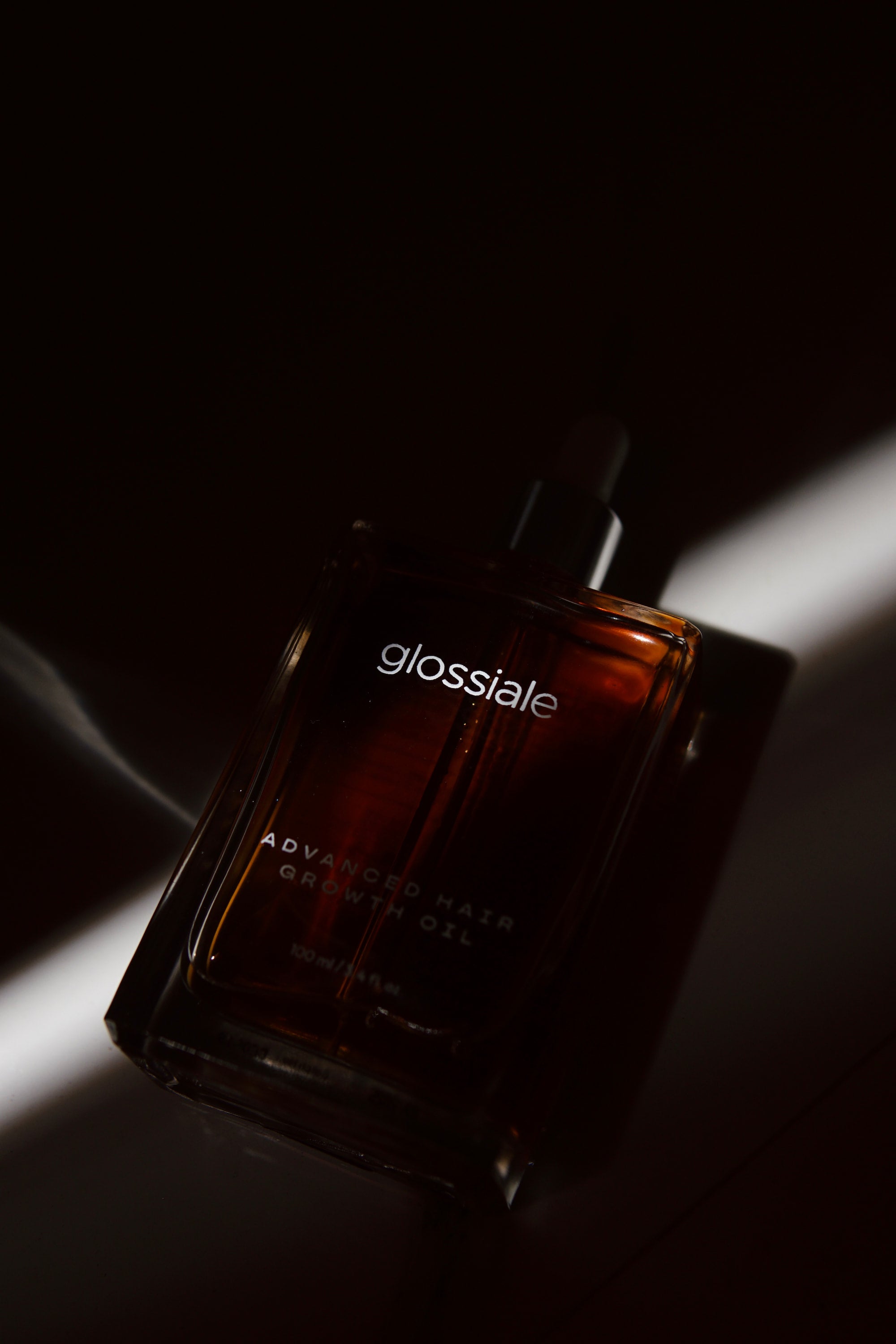 Glossiale hair oil bottle on a dark background