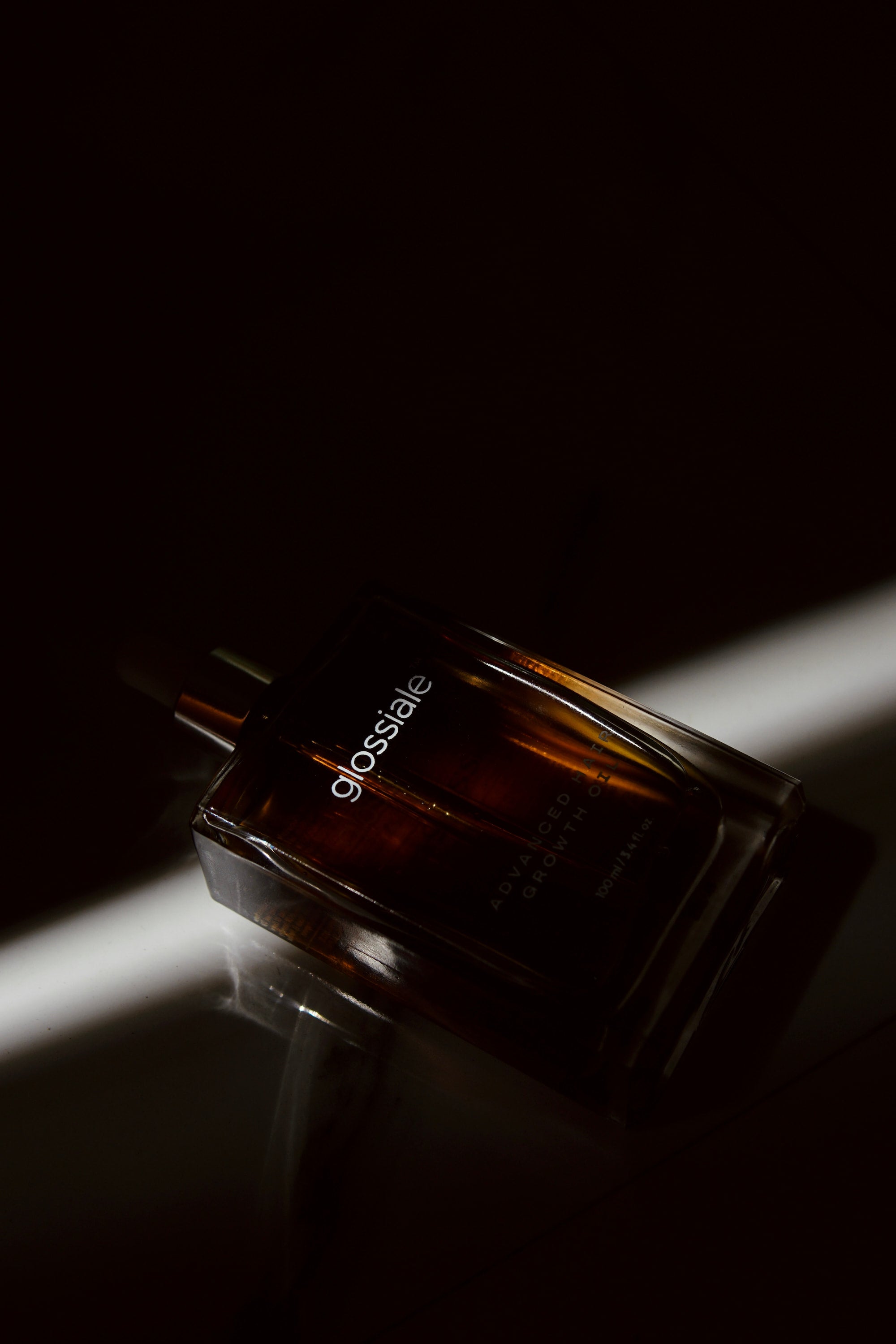 Glossiale hair oil bottle on a dark background
