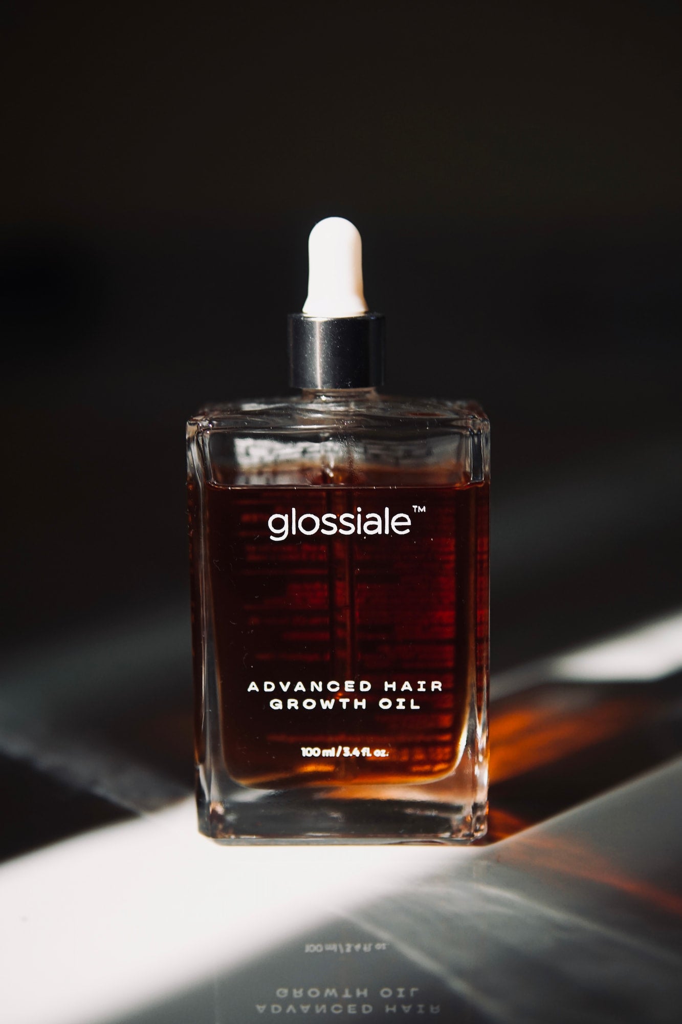 Glossiale Advanced Hair Growth Oil bottle with dropper on a dark background