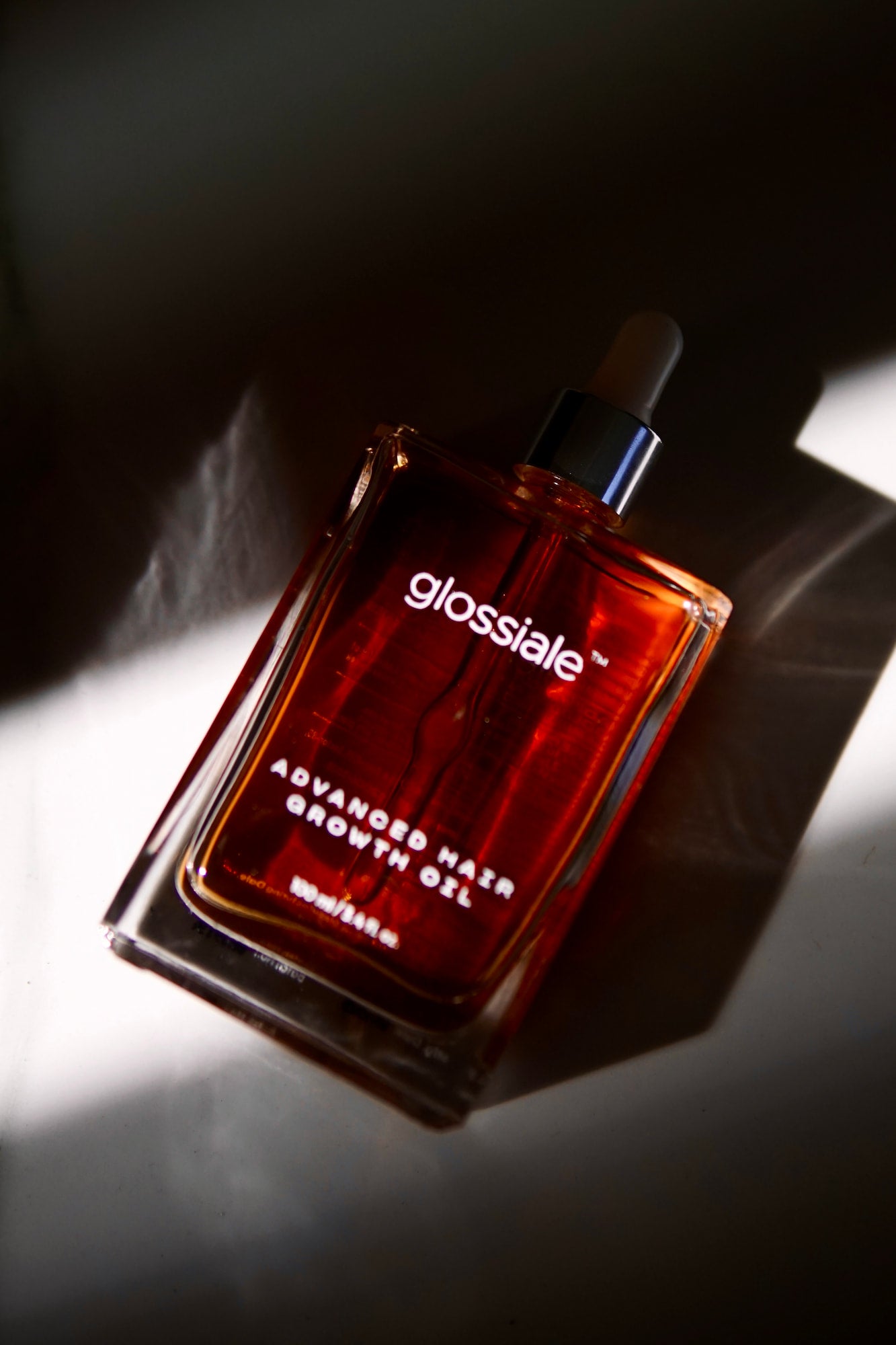 Glossiale Advanced Hair Growth Oil bottle on a dark background